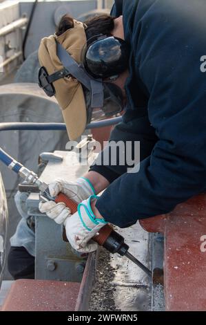 YOKOSUKA, Japon (5 janvier 2024) l’aviateur Alexa Flores, originaire de Corpus Christi, Texas, utilise un pistolet à aiguille pour préserver le pont d’envol du seul porte-avions déployé à l’avant de la marine américaine, l’USS Ronald Reagan (CVN 76), alors qu’il était commandant au port, Fleet Activities Yokosuka, janvier 5. Ronald Reagan, le navire amiral du Carrier Strike Group 5, fournit une force prête au combat qui protège et défend les États-Unis, et soutient les alliances, les partenariats et les intérêts maritimes collectifs dans la région Indo-Pacifique. Banque D'Images