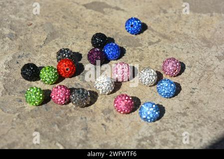 Belles boules lumineuses et multicolores avec des cristaux Swarovski disposés de manière chaotique sur un fond blanc vif en ciment. Banque D'Images