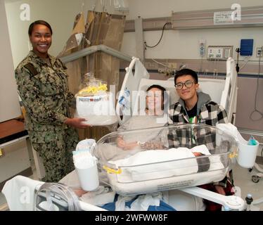 PORTSMOUTH, Virginie (janvier 2) C’est une «bonne année» pour deux marins qui sont devenus les parents du premier bébé né au Naval Medical Center Portsmouth (PNLP), janvier 1. IT2 Angelina Nguyen, stationnée au Naval Special Warfare Group 4 (NSWG4), a donné naissance à Mahina à 5:08 heures du matin le premier jour de la nouvelle année. Son mari, IT2 Kevin Nguyen, stationné à la Beach Master Unit (BMU) 2, était aux côtés de sa femme quand elle a reçu le panier First Baby Born 2024 fourni chaque année par le Oakleaf Club de Tidewater. Le lieutenant j.g. Mikala Tracy, l’infirmière du patient, a présenté le panier rempli de divers articles pour bébés à Th Banque D'Images