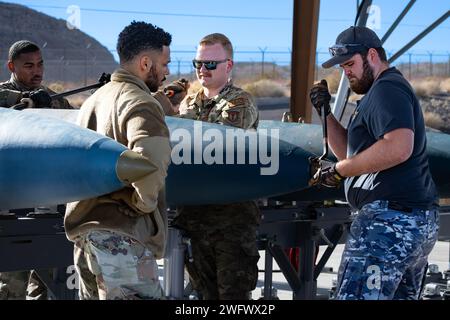 Trois aviateurs de l'US Air Force du 57th munitions Squadron à la base aérienne de Nellis (AFB) et du 31st munitions Squadron à Aviano AFB travaillent aux côtés de l'aviateur Marcus Blair, chef de file de la Royal Australian Air Force, à droite, pour installer des bouchons de nez sur une bombe inerte d'entraînement à la base aérienne de Nellis, Nevada, le 18 janvier, 2024. Red Flag-Nellis est un exercice d'entraînement au combat contesté qui offre à l'US Air Force et à ses alliés l'occasion de s'entraîner et de travailler ensemble vers des objectifs similaires. (Cette photo a été modifiée pour des raisons de sécurité en brouillant le badge d'identification) Banque D'Images