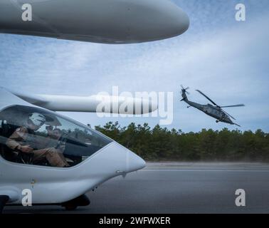 Le BETA technologies ALIA se prépare à décoller alors qu'un 41st Rescue Squadron HH-60W Jolly Green II décolle de la base aérienne d'Eglin, en Floride, le 11 janvier 2024. Les deux avions et les équipages ont participé à un exercice d'évacuation des blessés avec le HH-60 décollant et l'ALIA, un avion électrique de décollage et d'atterrissage, prenant le patient simulé pour des soins de plus haut niveau. Banque D'Images