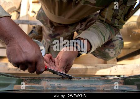 Le Sgt Treaon Sterling, sous-officier responsable des systèmes météorologiques, radar, aérodrome et météo du 409th Air Expeditionary Group, gratte une surface propre avant d'installer une nouvelle fenêtre sur une tour de contrôle mobile MSN-7 le 8 janvier 2024 à la base aérienne 201, Niger. Une tour de contrôle mobile peut être utilisée dans des environnements d'urgence pour permettre des opérations aériennes dans des environnements austères sans infrastructure permanente. Banque D'Images