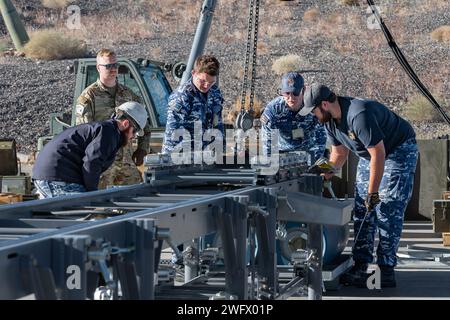 Le sergent d'état-major de l'US Air Force John Dyrud, à gauche, affecté au 31st munitions Squadron à la base aérienne d'Aviano (AFB), et les aviateurs de la Royal Australian Air Force inspectent le convoyeur d'assemblage de munitions (MAC) à la base aérienne de Nellis, Nevada, le 18 janvier 2024. Les Macs agissent comme des chaînes de montage pour aider les aviateurs à construire efficacement des munitions. (Cette photo a été modifiée pour des raisons de sécurité en brouillant le badge d'identification) Banque D'Images