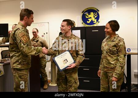 Colonel Ryan Garlow de l'US Air Force, à gauche, commandant de la 100th Air ravitaillement Wing, et le sergent-chef Tiffany Griego, à droite, chef de commandement de la 100e ARW, félicitent le sergent-chef Brandon Kapp, gestionnaire du déploiement de l’unité du 100e Escadron de maintenance, pour avoir été l’aviateur prêt de la semaine à la Royal Air Force Mildenhall, en Angleterre, le 18 janvier 2024. Un gestionnaire de déploiement d’unité est responsable de l’exécution de toutes les fonctions administratives des aviateurs qui sont déployés pour accomplir des opérations d’urgence en temps de paix ou en temps de guerre. Banque D'Images