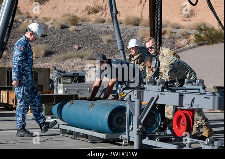 Les aviateurs de la Royal Australian Air Force (RAAF) et les aviateurs de l'US Air Force font tourner les bombes pour attacher des crochets avant de les charger sur un convoyeur d'assemblage de munitions à la base aérienne de Nellis, Nevada, le 18 janvier 2024. Les aviateurs de la RAAF sont à Nellis pour participer à Red Flag Nellis 24-1. L'exercice d'entraînement au combat offre à l'US Air Force et à ses alliés l'occasion de s'entraîner et de travailler ensemble à des objectifs similaires. (Cette photo a été modifiée pour des raisons de sécurité en brouillant le badge d'identification) Banque D'Images