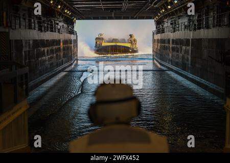 Un marin américain observe le Landing Craft, Air Cushion 58, attaché à l'Assault Craft Unit 5, se préparant à entrer dans le pont du quai de transport amphibie USS Somerset (LPD 25) transportant le personnel et l'équipement de la 15th Marine Expeditionary Unit dans l'océan Pacifique, 5 janvier 2024. Le 15th MEU est actuellement embarqué à bord du Boxer Amphibious Ready Group menant des opérations de formation et de routine intégrées dans la 3rd Fleet américaine. Banque D'Images