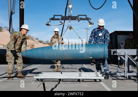 L'aviateur senior de l'US Air Force Tadeo Rodriguez, à gauche, affecté au 31e escadron de munitions à la base aérienne d'Aviano (AFB), le Sgt Jordan Render, du 57e escadron de munitions, au milieu, et Luke Mather, chef de file de l'aviation de la Royal Australian Air Force, à droite, télécharge une bombe d'entraînement inerte sur le convoyeur d'assemblage de munitions pour préparer la construction d'un GBU-31V1 à la base aérienne de Nellis, Nevada, le 18 janvier 2024. Une fois construite, la bombe d'entraînement inerte sera chargée sur un avion de combat F-35 Lightning II. (Cette photo a été modifiée pour des raisons de sécurité en brouillant le badge d'identification) Banque D'Images