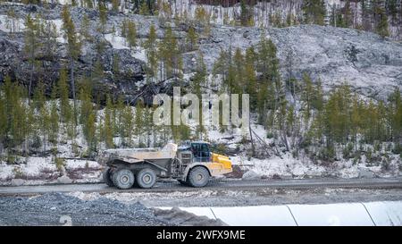 Camion à benne basculante se déplaçant sur une route d'accès au pied d'une montagne Banque D'Images