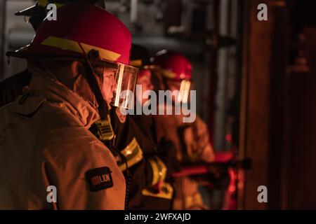 GRANDS LACS, il. (10 janvier 2024) des marins de la nouvelle accession manient un tuyau d'incendie au cours de lutte contre les incendies à bord des navires (GSF) de surface Warfare Engineering Schools Command Great Lakes (commandement des écoles d'ingénierie de guerre de surface des Grands Lacs) à la base navale de Great Lakes. Le programme de deux jours comprend des leçons en classe relatives à la chimie du feu, des classes de feux (alpha, bravo et charlie), l'organisation des pompiers, les extincteurs portatifs, l'équipement de protection, ainsi que les appareils respiratoires autonomes pendant la première journée, et les laboratoires d'entraînement à la lutte contre les incendies en direct couvrent les tuyaux sauvages, la manipulation des tuyaux et les procédures de lutte contre les incendies pendant la deuxième journée. GSF Grea Banque D'Images