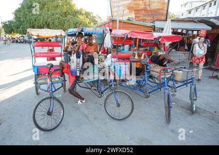 Toliara, Madagascar - 01 mai 2019 : groupe d'hommes malgaches inconnus avec leurs chariots de pousse-pousse à vélo attendant les passagers, posant pour la caméra. Ces t Banque D'Images