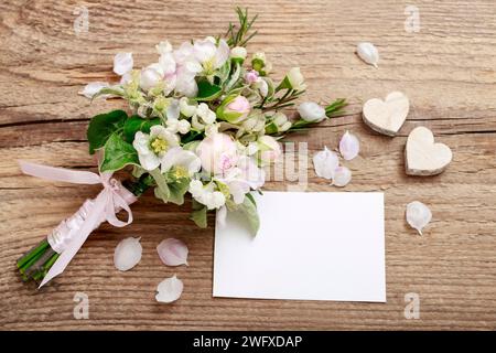 Bouquet romantique avec des brindilles fleuries de pommier, fleurs de lilly de la vallée, roses roses et camelaucium (fleur de cire). Fond en bois. Banque D'Images