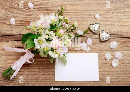 Bouquet romantique avec des brindilles fleuries de pommier, fleurs de lilly de la vallée, roses roses et camelaucium (fleur de cire). Fond en bois. Banque D'Images