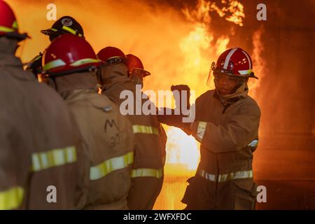 GRANDS LACS, il. (10 janvier 2024) des marins de la nouvelle accession manient un tuyau d'incendie au cours de lutte contre les incendies à bord des navires (GSF) de surface Warfare Engineering Schools Command Great Lakes (commandement des écoles d'ingénierie de guerre de surface des Grands Lacs) à la base navale de Great Lakes. Le programme de deux jours comprend des leçons en classe relatives à la chimie du feu, des classes de feux (alpha, bravo et charlie), l'organisation des pompiers, les extincteurs portatifs, l'équipement de protection, ainsi que les appareils respiratoires autonomes pendant la première journée, et les laboratoires d'entraînement à la lutte contre les incendies en direct couvrent les tuyaux sauvages, la manipulation des tuyaux et les procédures de lutte contre les incendies pendant la deuxième journée. GSF Grea Banque D'Images