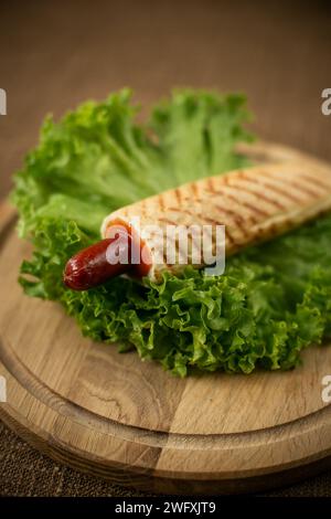 hot-dog français sur une planche en bois sur un fond de bois, restauration rapide et espace de copie. gros plan Banque D'Images