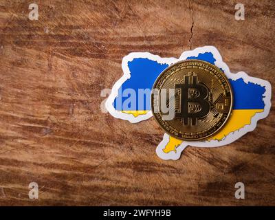 Vue de dessus bitcoin et drapeau de l'ukraine sur un fond en bois avec espace de copie. Banque D'Images