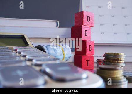 Cubes en bois avec DETTE DE mot entouré d'argent et calculatrice. Concept financier. Banque D'Images