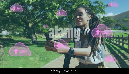 Image de nuages avec des flèches sur la femme à l'aide d'un smartphone debout sur scooter dans le parc Banque D'Images