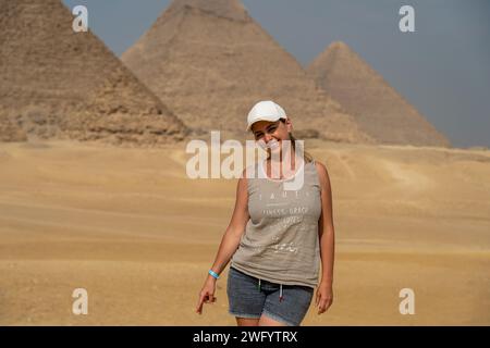 Une jeune fille touriste se tient au milieu du désert sur fond des pyramides égyptiennes Banque D'Images