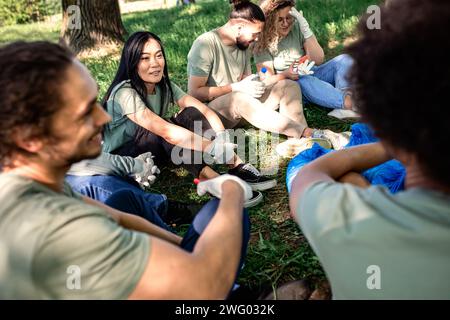 Groupe multiethnique de volontaires se reposant après le nettoyage du parc de la ville. Banque D'Images