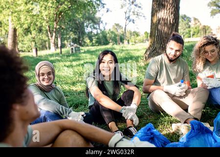 Groupe multiethnique de volontaires se reposant après le nettoyage du parc de la ville. Banque D'Images