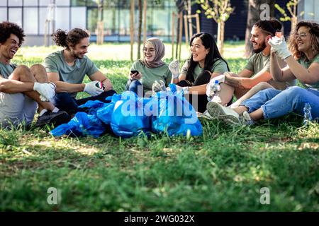 Groupe multiethnique de volontaires se reposant après le nettoyage du parc de la ville. Banque D'Images