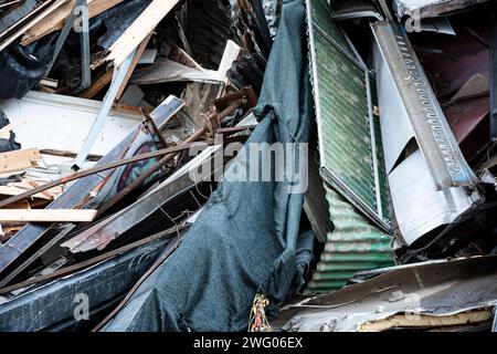 Gros plan de débris de construction à la suite d'une démolition. Planches de bois cassées, tissu déchiré et pile de feuilles de fer galvanisées ondulées cassées Banque D'Images
