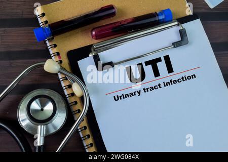 Concept d'UTI - infection des voies urinaires écrire sur la paperasse avec stéthoscope isolé sur fond de bois. Banque D'Images