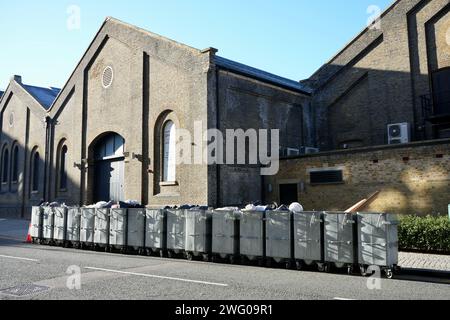 Des poubelles commerciales alignées dans la rue à Woolwich Arsenal. Woolwich, Londres, Royaume-Uni, 19 janvier 2024. Banque D'Images