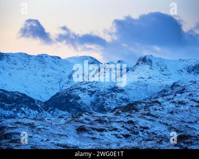 Neige sur les Langdale Pikes au coucher du soleil depuis Ambleside, Lake District, Royaume-Uni. Banque D'Images