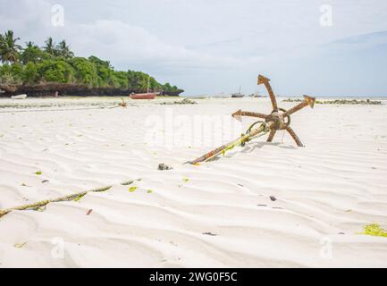 Ancre de bateau sur la plage. Plage à marée basse avec ancre rouillée et bateaux. Paysage de marée basse. Style de vie de Zanzibar. Transport tropical. Banque D'Images