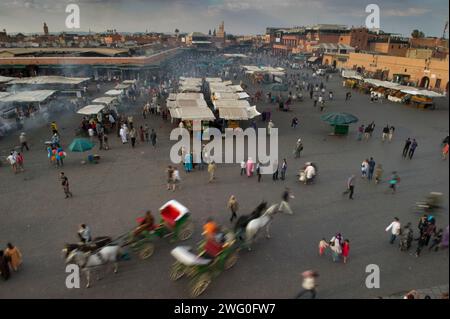 Les calèches transportent les piétons à travers le marché marocain animé tandis que d'autres font des emplettes et mangent. Banque D'Images