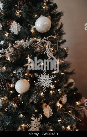 sapin de noël orné d'ampoules blanches, de flocons de neige et de lumières douces Banque D'Images