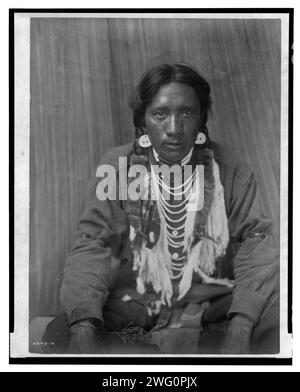 Chemise - Kalispel, c1910. La photographie montre un homme de Kalispel, portrait en pied, face à l'avant, assis avec les jambes croisées, les mains reposant sur les genoux. Banque D'Images