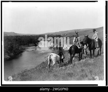 Trois Indiens Piegan et quatre chevaux sur une colline au-dessus de la rivière, c1910. Banque D'Images