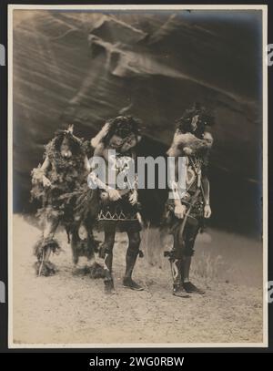 Dieux de guerre Yeibichai, 1904, c1905. La photographie montre trois natifs : Tonenili, Tobadzischini et Nayenezgani, en robe de cérémonie, photographiés sur fond rocheux sombre. Banque D'Images