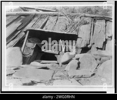 Entrée d'un Sweat-House Yurok, c1923. Trou abrité en monticule de terre bordé de planches, gros rochers en premier plan. Banque D'Images