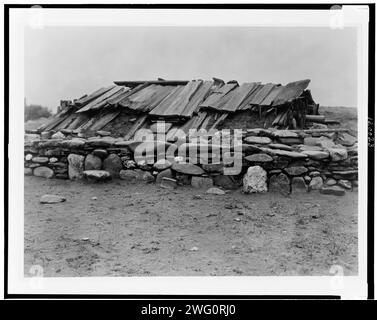 Hupa maison de sueur, 1923. Bâtiment souterrain recouvert d'un toit en planches de bois, entouré d'un mur de gros rochers. Banque D'Images