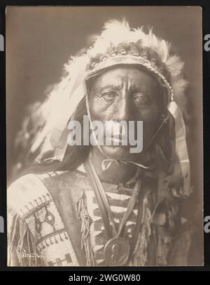 Jack Red Cloud, 1907. La photographie montre le portrait tête et épaules de Jack Red Cloud, debout, portant une coiffe complète, des vêtements traditionnels et un médaillon, face à l'avant. Banque D'Images