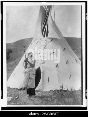 Slow Bull, c1907. Homme Dakota debout à l'extérieur de tipi regardant vers le haut. Banque D'Images