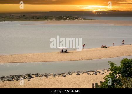 Les gens sur la plage de l'entrée de marée de la réserve naturelle de Zwin à la côte de la mer du Nord au coucher du soleil, à la frontière entre la Belgique et les pays-Bas Banque D'Images