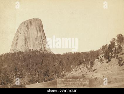 Tour du diable. Devil's Tower ou Bear Lodge. (Mato [i.e. Mateo] Tepee des Indiens), vu du côté est. Situé près de la rivière Belle fourche, dans le Wyoming []. Vue lointaine de la Tour du Diable sur la gauche ; arbres au premier plan. Banque D'Images