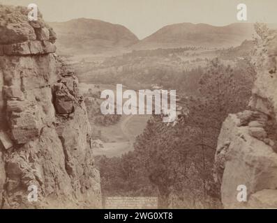 Echo Canyon regardant à travers Sioux Pass sur FE et MV Ry, Hot Springs, SD, 1891. Maison et route dans la zone des plaines comme vu d'en haut et entre deux grandes formations rocheuses ; montagnes au loin. Banque D'Images