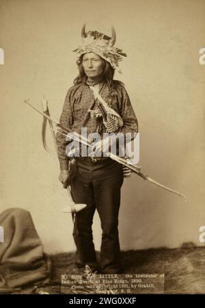 Little, instigateur de la révolte indienne à Pine Ridge, 1890, 1891. Little, chef de groupe Oglala, portrait studio en pied, debout, face à l'avant, porter une coiffe en corne, un pantalon et une chemise, et tenir un arc, des flèches et un tomahawk. Banque D'Images