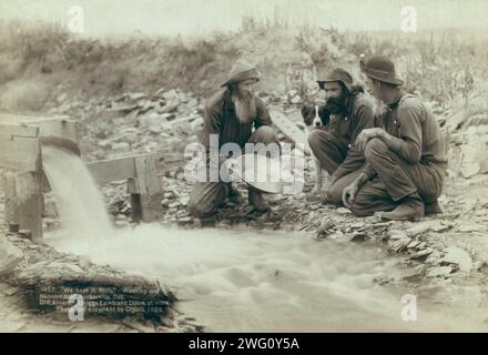 Nous l'avons riche. Laver et ramasser de l'or, Rockerville, Dak. Vieux, Spriggs, Lamb et Dillon au travail []. Montrant trois hommes, avec un chien, à la recherche d'or dans un ruisseau. Titre transcrit à partir de l'élément. Banque D'Images