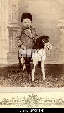Portrait d'un garçon assis sur un cheval jouet, fin 19e cent - début 20e cent. Cette collection contient 136 photographies d'Irkoutsk de la fin du XIXe siècle et du début du XXe siècle. Les photographies montrent des vues de la ville d'Irkoutsk et de la campagne de la province d'Irkoutsk ; les moyens de transport ; et les citoyens, y compris leur mode de vie, les activités sociales et les formes de divertissement. Musée d'histoire municipale d'Irkoutsk Banque D'Images