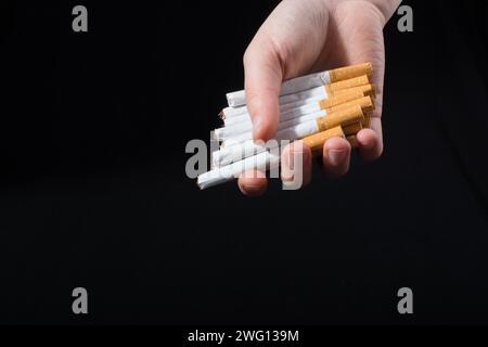 La main est de donner des paquet de cigarettes sur fond noir Banque D'Images