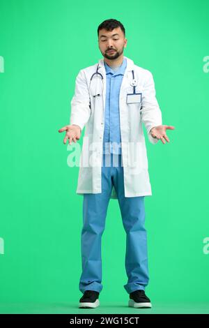 Le médecin, en pleine hauteur, sur un fond vert, étend ses mains Banque D'Images