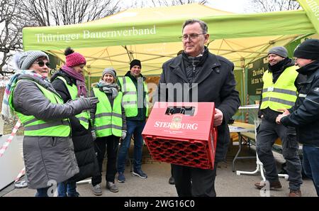 02 février 2024, Thuringe, Erfurt : Bodo Ramelow (Die Linke), ministre-président de Thuringe, visite le camp des agriculteurs de l'Association des Thuringe devant le Parlement de l'État de Thuringe et emporte une caisse de bière. Le vice-président de l'Association des agriculteurs de Thuringe avait fait un pari avec le ministre de l'Agriculture de Thuringe pour une caisse de bière, perdue et avait remis le pari à Ramelow. En marge de la session de trois jours du Parlement de l'État de Thuringe, les agriculteurs demandent l'annulation de la réduction du diesel agricole, une exonération fiscale pour les biocarburants et une réduction de la consommation Banque D'Images