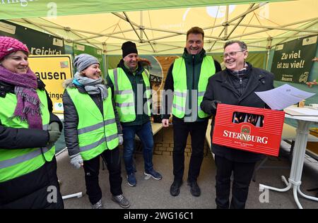 02 février 2024, Thuringe, Erfurt : Bodo Ramelow (r, Die Linke), ministre-président de Thuringe, visite le camp des agriculteurs de l'Association des Thuringe devant le Parlement de l'État de Thuringe et emporte une caisse de bière. Lars Fliege (2e à partir de la droite), vice-président de l'Association des agriculteurs de Thuringe, avait fait un pari avec le ministre de l'Agriculture de Thuringe pour une caisse de bière, perdue et avait remis le pari à Ramelow. En marge de la session de trois jours du Parlement de l'État de Thuringe, les agriculteurs exigent l'annulation de la réduction du diesel agricole, une exonération fiscale fo Banque D'Images