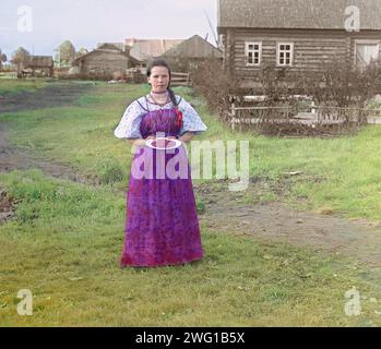 Fille aux fraises [Empire russe], 1909. Jeune paysanne russe offrant des baies aux visiteurs de son izba, une maison traditionnelle en bois, dans une zone rurale le long de la rivière Sheksna près de la petite ville de Kirillov. Banque D'Images